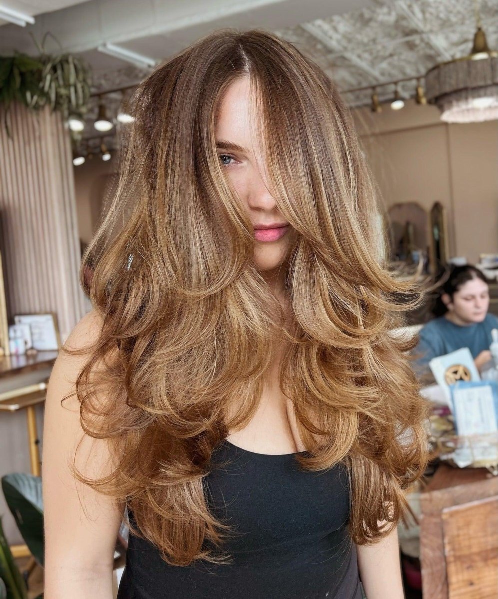 Long layered hair styled into a soft 90s blowout