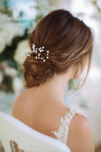 4. Low Chignon with Pearl Pins and Side Part for hairstyles for long hair wedding ideas