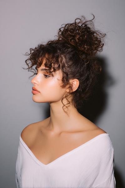 25. Messy Top Bun with Curly Bangs for Hairstyles for School Curly Hair Bun and a Soft Halo