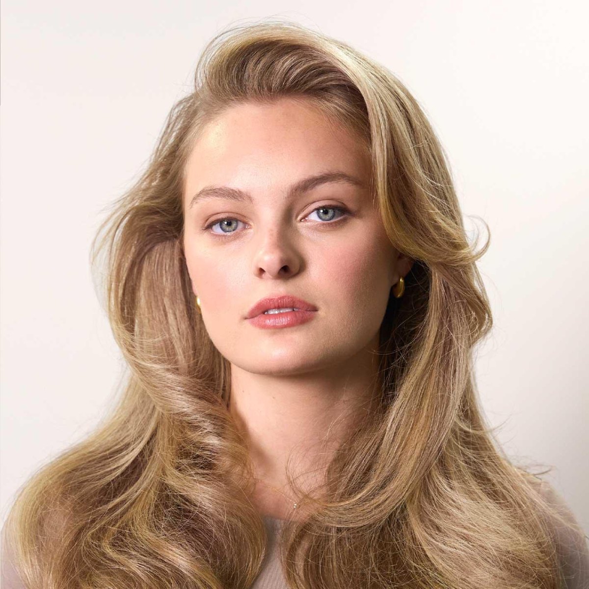 Soft beige blonde hair styled as 90s blowout waves