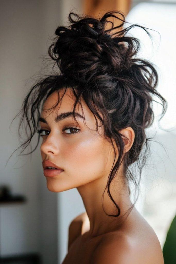 Dark hair messy high bun updo with loose pieces